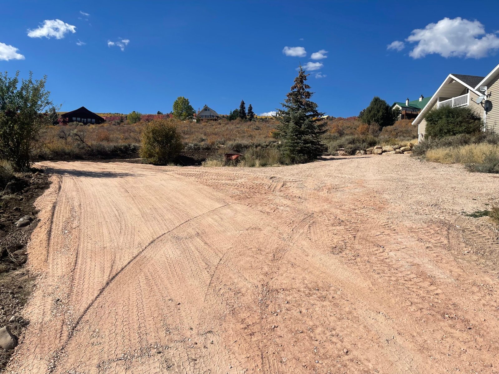 An image of a backyard that was recently leveled and graded. The dirt has tracks from the machinery that did the leveling.